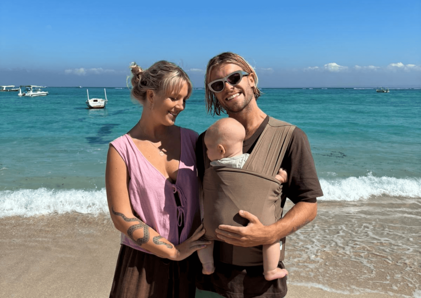 Parents with their newborn travelling using a baby carrier