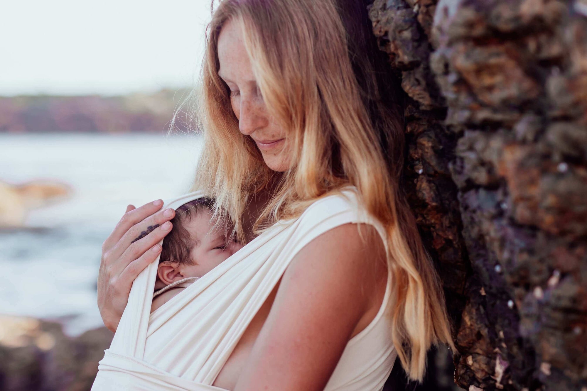 Mum babywearing at the beach using BabyDink Carrier in Color Sand