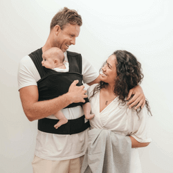 Mum and Dad babywearing their newborn in Black BabyDink carrier