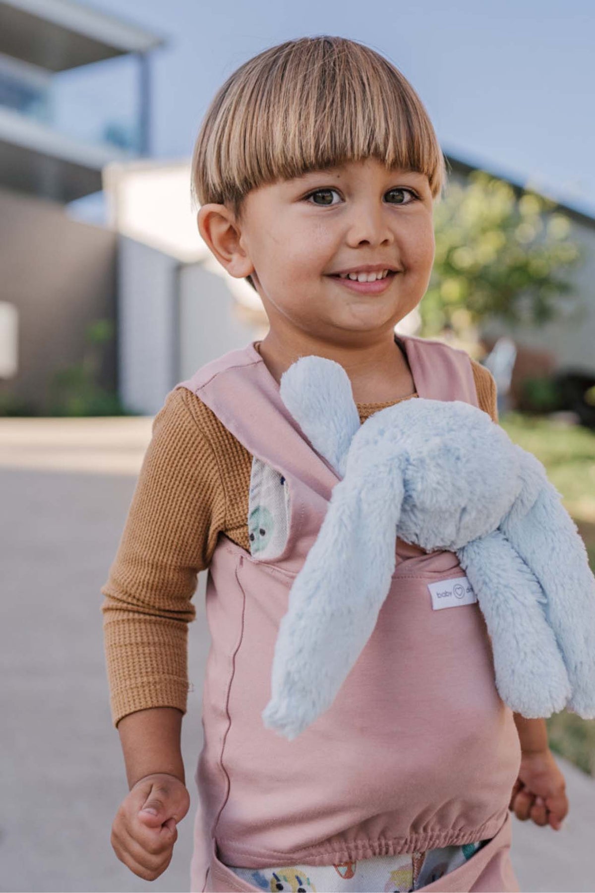 Child happily carrying doll in our doll carrier