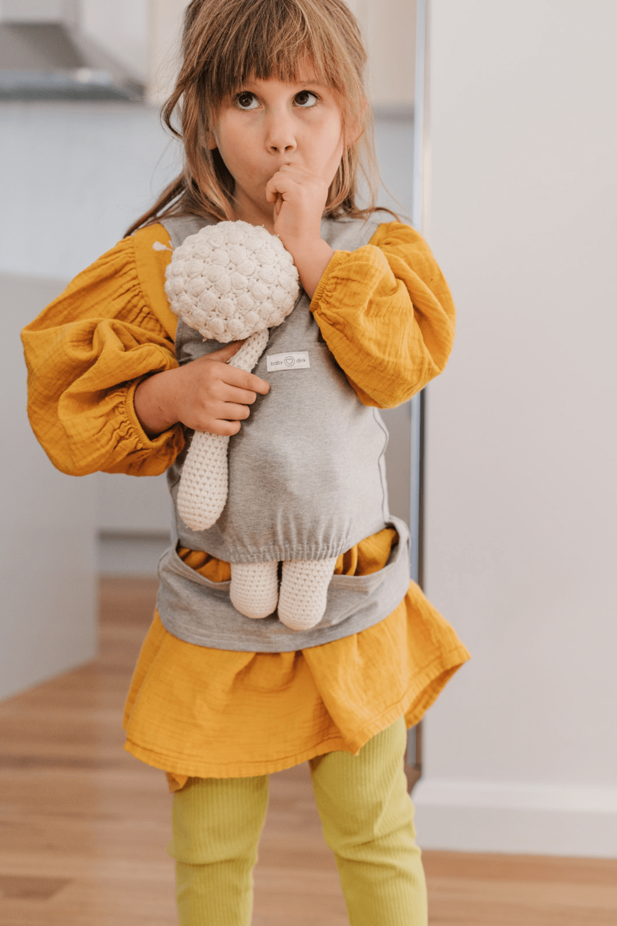 Child happily carrying doll in our doll carrier